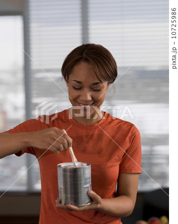 Front view of woman holding paint can and paintbrush 10725986