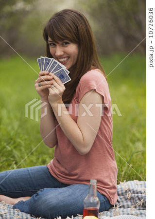 Young woman playing cards in orchard Young woman playing cards in orchard 10726036