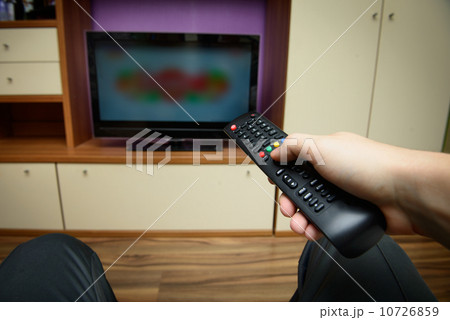 Man sitting on a sofa watching tv holding remote control Man sitting on a sofa watching tv holding remote control 10726859