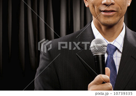 USA, Utah, Provo, Close-up of businessman with microphone standing in front of black curtain, mid section USA, Utah, Provo, Close-up of businessman with microphone standing in front of black curtain, mid section 10739335