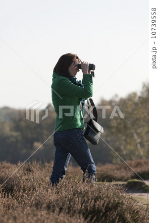 The Netherlands, Veluwezoom, Posbank, Woman in countryside looking through binoculars The Netherlands, Veluwezoom, Posbank, Woman in countryside looking through binoculars 10739558
