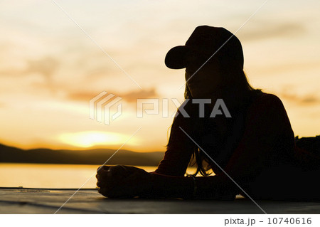 USA, California, Silhouette of young woman relaxing on beach at sunset USA, California, Silhouette of young woman relaxing on beach at sunset 10740616