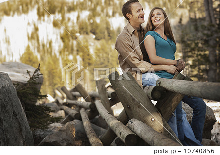 Laughing couple sitting on log fence 10740856