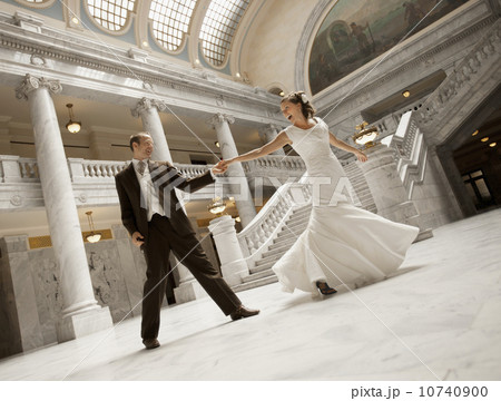 Bride and groom holding hands in mansion 10740900