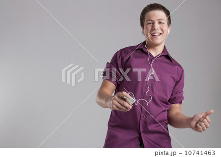 Portrait of smiling teenager listening mp3 player, studio shot Portrait of smiling teenager listening mp3 player, studio shot 10741463