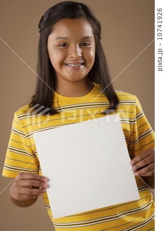 Studio portrait of girl (10-11) holding blank sheet of paper Studio portrait of girl (10-11) holding blank sheet of paper 10741926