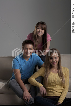 Portrait of teenage boy (16-17) and girl (16-17) with young friend 10742287