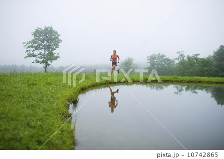 USA, Vermont, Landgrove, Woman jogging by lake 10742865