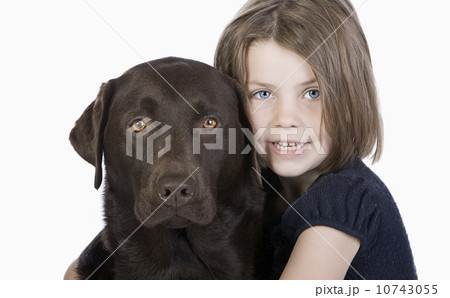 Studio portrait of smiling girl (6-7) hugging chocolate labrador 10743055