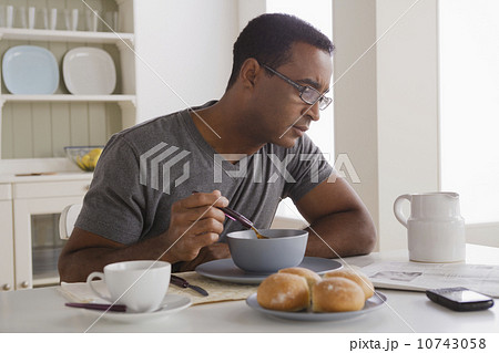 Mature man eating breakfast and reading newspaper Mature man eating breakfast and reading newspaper 10743058