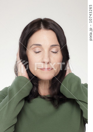 Studio portrait of mature woman covering ears Studio portrait of mature woman covering ears 10743265