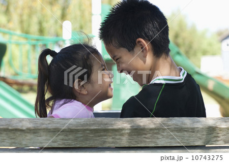 Brother and sister (4-13) face to face at playground 10743275