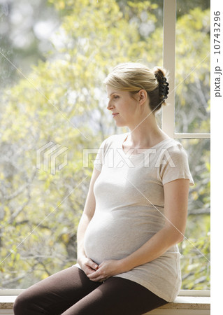 Mid adult pregnant woman sitting on porch 10743296