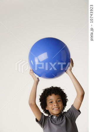 Studio portrait of boy (8-9) holding blue ball Studio portrait of boy (8-9) holding blue ball 10743923