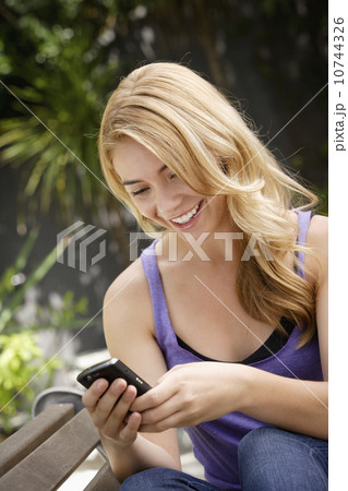 Young woman text-messaging in park 10744326