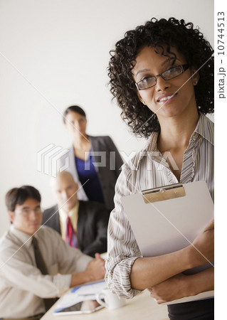 Businesswoman looking at camera, business team in background Businesswoman looking at camera, business team in background 10744513