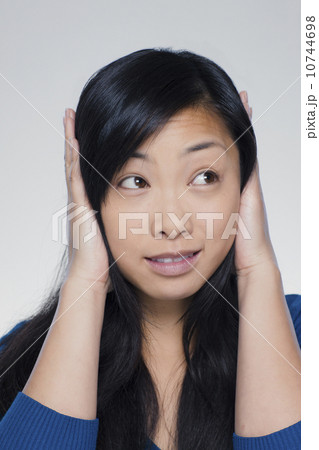 Studio portrait of young woman covering ears Studio portrait of young woman covering ears 10744698