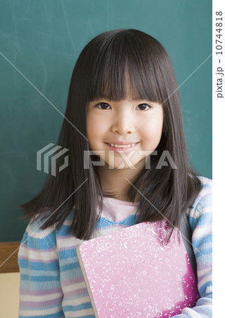 Smiling girl (6-7) against blackboard 10744818