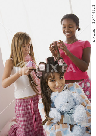 Three girls (10-11) doing hair at slumber party Three girls (10-11) doing hair at slumber party 10744921