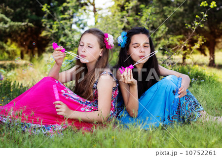 Portrait of two girls playing with bubble blower Portrait of two girls playing with bubble blower 10752261