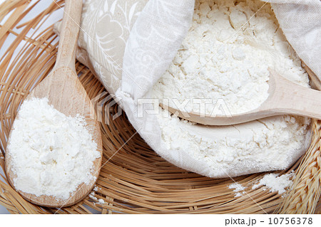 Flour and wheat grain with wooden spoon on a wicker basket. 10756378
