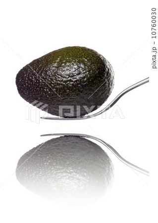 an avocado laying on a fork with reflection, isolated on white 10760030
