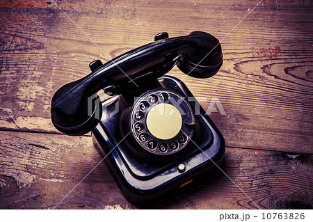 Old black phone with dust and scratches on wooden floor 10763826