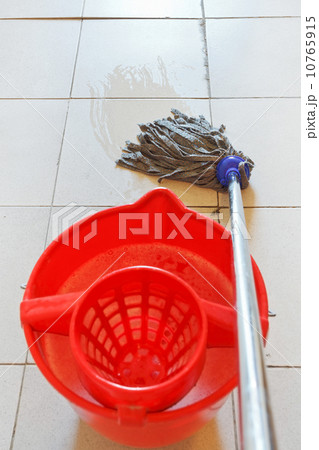 mopping the tile floor by swab and red bucket 10765915