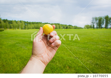 Hand with golf ball over a golf course Hand with golf ball over a golf course 10770055