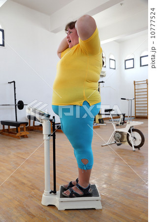 impressed overweight woman on scales in gym 10777524