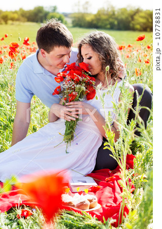 Young happy couple on a meadow full of poppies Young happy couple on a meadow full of poppies 10778831