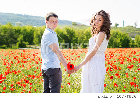 Young happy couple on a meadow full of poppies 10778926