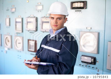 young smiling engineer taking notes in control room young smiling engineer taking notes in control room 10795843