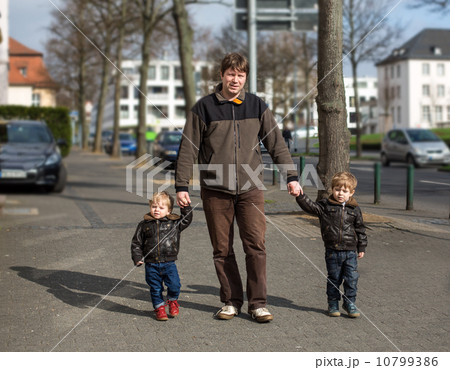 Young man and two little boys walking through spring city 10799386