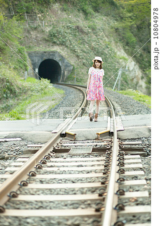 お腹のローカル線の線路で遊ぶワンピースを着た可愛らしい女の子の写真素材