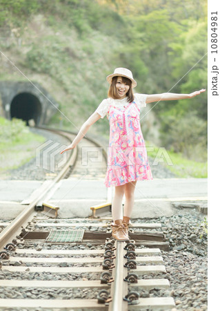 お腹のローカル線の線路で遊ぶワンピースを着た可愛らしい女の子の写真素材