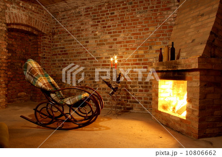 Rocking chair by the fireplace in brick room Rocking chair by the fireplace in brick room 10806662