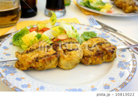 Grilled chicken fillet on metal skewer with salad 10813022