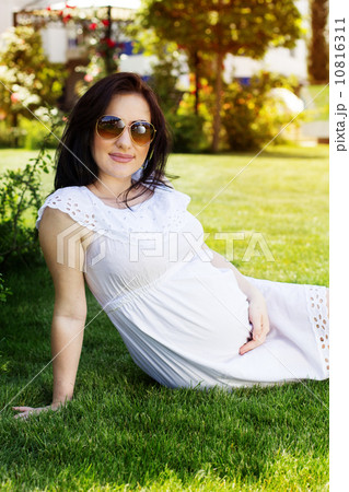 Pregnant woman resting in park with green grass 10816311