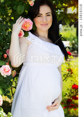 Pregnant woman resting in park with green grass 10816316