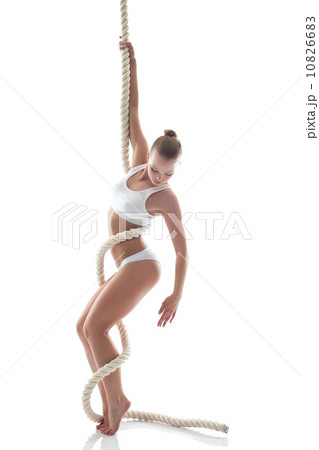 Pretty slim gymnast posing on rope in studio 10826683