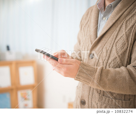 ニットのカーディガンを着てスマートフォンを操作する男性 ニットのカーディガンを着てスマートフォンを操作する男性 10832274