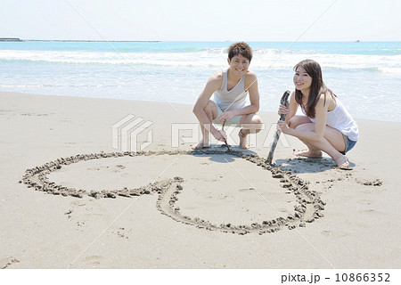 砂浜にハートを描く若いカップル 砂浜にハートを描く若いカップル 10866352