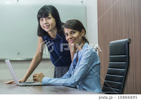 Two Female Asian executives having a discussion at the desk, looking into the laptop Two Female Asian executives having a discussion at the desk, looking into the laptop 10866895