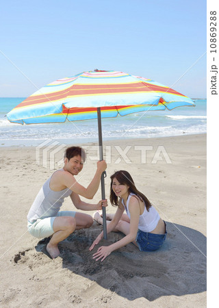 ビーチパラソルを立てる若いカップル ビーチパラソルを立てる若いカップル 10869288