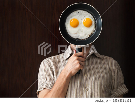 Young man portrait behind black frying pan with scrabbled eggs Young man portrait behind black frying pan with scrabbled eggs 10881231