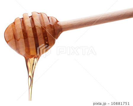 Honey dripping from a wooden honey dipper isolated on white back 10881751