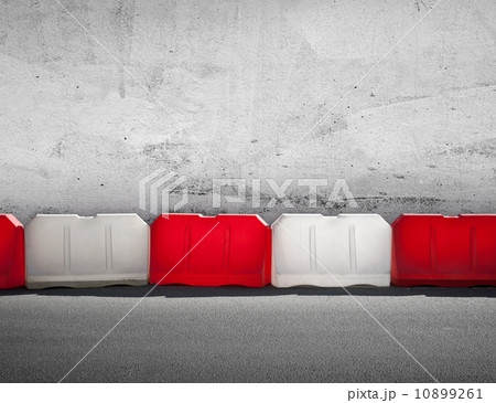 Red and white road barrier above concrete wall 10899261