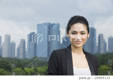 Happy asian looking business woman in front of city. 10904115