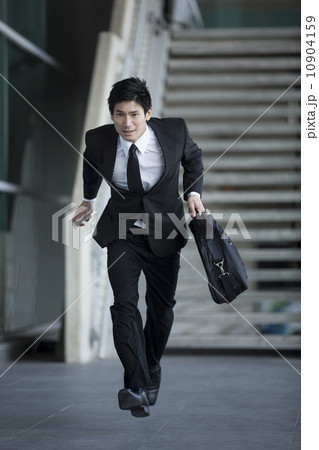 Asian businessman running through city 10904159